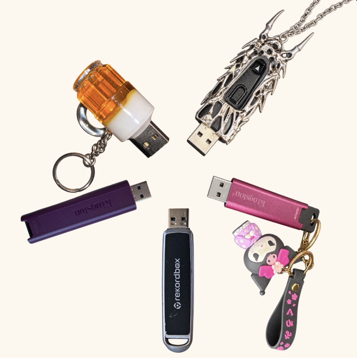 Five DJs' USB drives with their charms, arranged in a circle